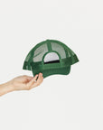 Green mesh cap held by a hand on a white background