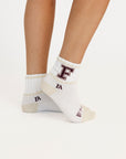 'F' logo on white socks on a light background