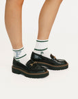 Black loafers with white socks featuring green and blue text on a white background