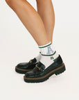 Black loafers with white socks featuring green and blue text on a white background