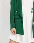 Green blazer over a white outfit on a plain background