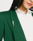 Person wearing a green blazer with white shirt on a plain background