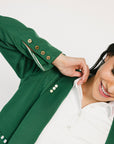 Person wearing a green jacket with gold buttons on a white background