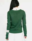 Woman wearing a green Dorothy sweater with a white collar against a white background