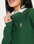 Green sweater with a small logo worn by a person, on a white background