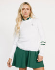 Woman wearing a white Dorothy sweater with green accents and a green skirt on a white background