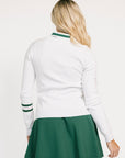 Woman wearing a white Dorothy sweater with green accents and a green skirt on a white background