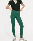 Person wearing a black top and green leggings on a white background