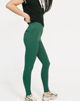 Person wearing green leggings and a black top on a white background