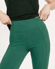 Person wearing green pants and a black top on a light gray background