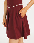 Woman wearing a maroon dress with a white logo on a white background