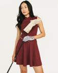 Woman in a burgundy dress holding a golf club and wearing gloves on a white background
