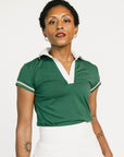Woman wearing a green polo shirt with white trim on a white background