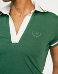 Woman wearing a green polo shirt with white trim on a white background