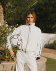 A model wearing the white Lyla Jacket holding a soccer ball.