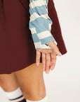 Woman wearing a blue and white striped sweater with 'FORE' text on a plain background showing the shirt's thumbholes
