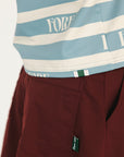 Close-up of a striped shirt with visible branding and burgundy pants with a brand tag.