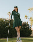A female model wearing a long sleeve green and white ribbed baselayer top with raglan sleeves and colorblocking.