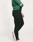 Person wearing a green long-sleeve shirt and black leggings on a white background