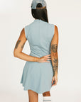 Woman wearing a light blue sleeveless dress with a logo and a matching cap on a white background