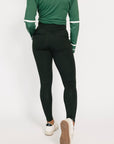 Person wearing a green long-sleeve top and black leggings on a white background