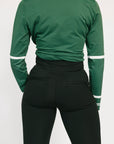 Green long-sleeve top and black pants on a white background