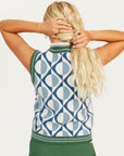 Woman wearing a patterned sleeveless sweater and green pants on a white background