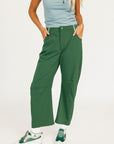 Person wearing green pants and a light blue top on a white background