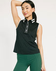 Woman wearing a black sleeveless Moore Polo with white collar and text details on a plain background