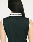Woman wearing a black sleeveless Moore Polo with white collar and text details on a plain background