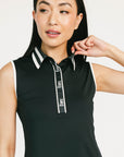 Woman wearing a black sleeveless Moore Polo with white collar and text details on a plain background