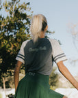 A woman wearing a blue and white striped t-shirt with the words 'chasing balls' on it, paired with a green skirt.