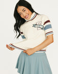Woman wearing a Macbeth Turtleneck sweater, light blue skirt, and white sneakers on a white background