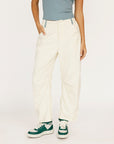 Person wearing white pants and green sneakers on a plain background