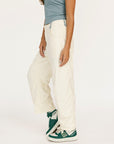 Person wearing white pants and green sneakers on a plain background