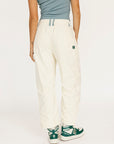 Person wearing white pants and green sneakers on a plain background