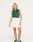 Woman wearing a green sleeveless Moore Polo shirt with white trim on a plain background