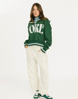 Woman wearing a green sweatshirt with 'FORE' text on a white background