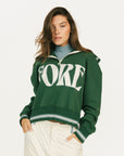 Woman wearing a green sweatshirt with 'FORE' text on a white background