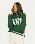 Woman wearing a green sweatshirt with 'FORE' text on a white background