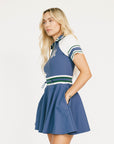 Woman wearing a blue dress with white and green accents on a white background.
