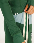 Person wearing a green Marie long-sleeve shirt and light blue shorts with a cap on a white background