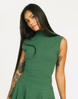 Woman wearing a green dress Manhattan Mock Neck against a white background
