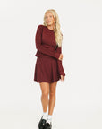 Woman wearing a burgundy Marie Long Sleeve with a logo on a white background