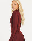 Woman wearing a burgundy Marie Long Sleeve with a logo on a white background