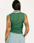 Person wearing a green sleeveless top and light blue skirt on a white background
