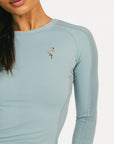 Light blue long-sleeve shirt with a small logo worn by a person on a white background