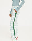 Person wearing a light blue long-sleeve top and plaid pants with green stripes on a white background