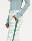 Person wearing a light blue long-sleeve top and plaid pants with green accents on a white background