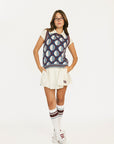 Woman wearing a patterned Yale Sweater Vest over a white shirt and skirt on a white background
